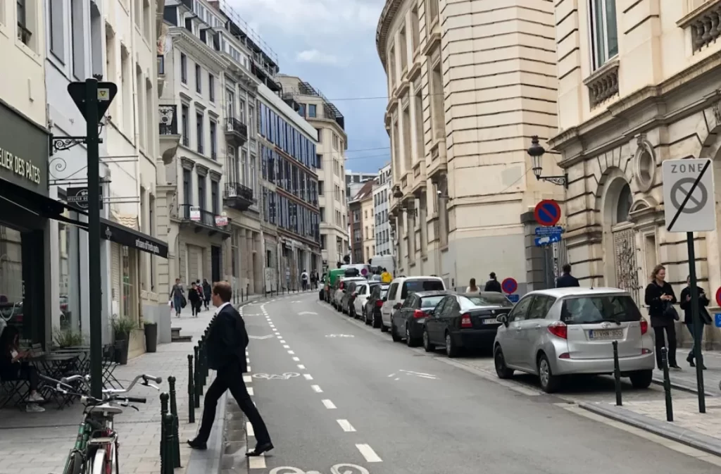 Busy street in Brussels with parked cars.