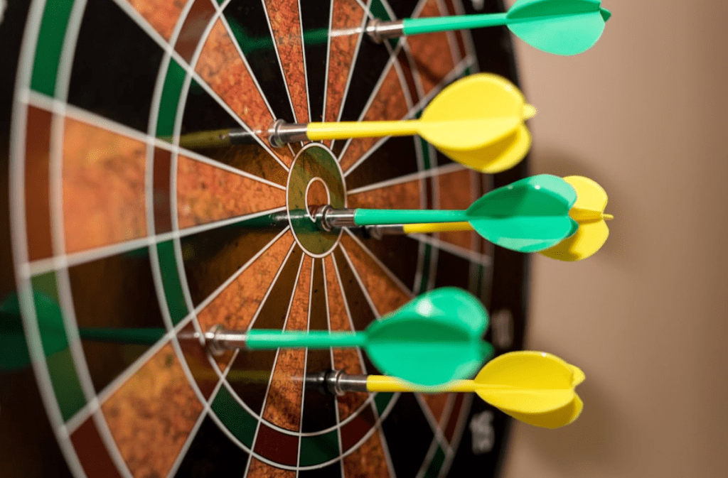 Green and yellow darts on a dartboard target.