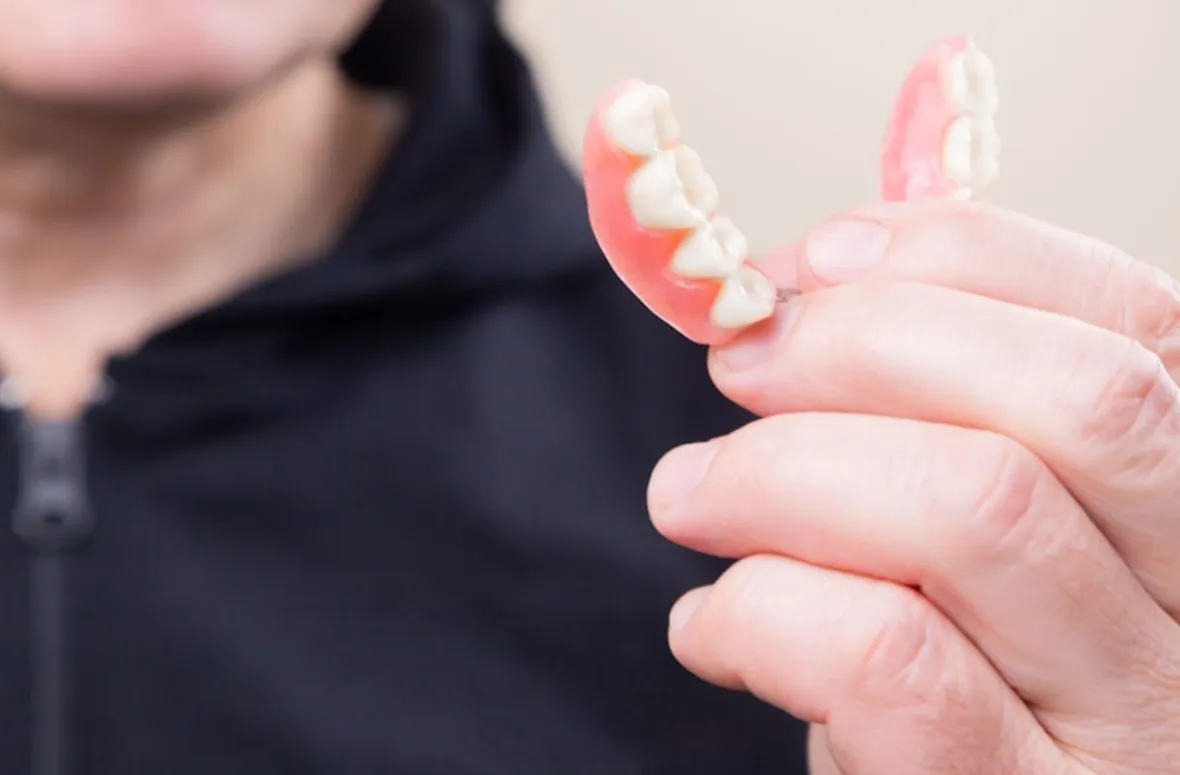 Hand holding hybrid dentures close-up.