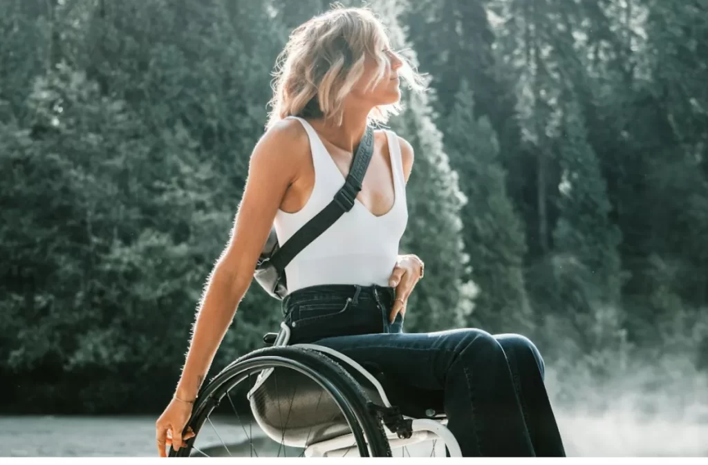 Woman in wheelchair outdoors, looking into the distance.
