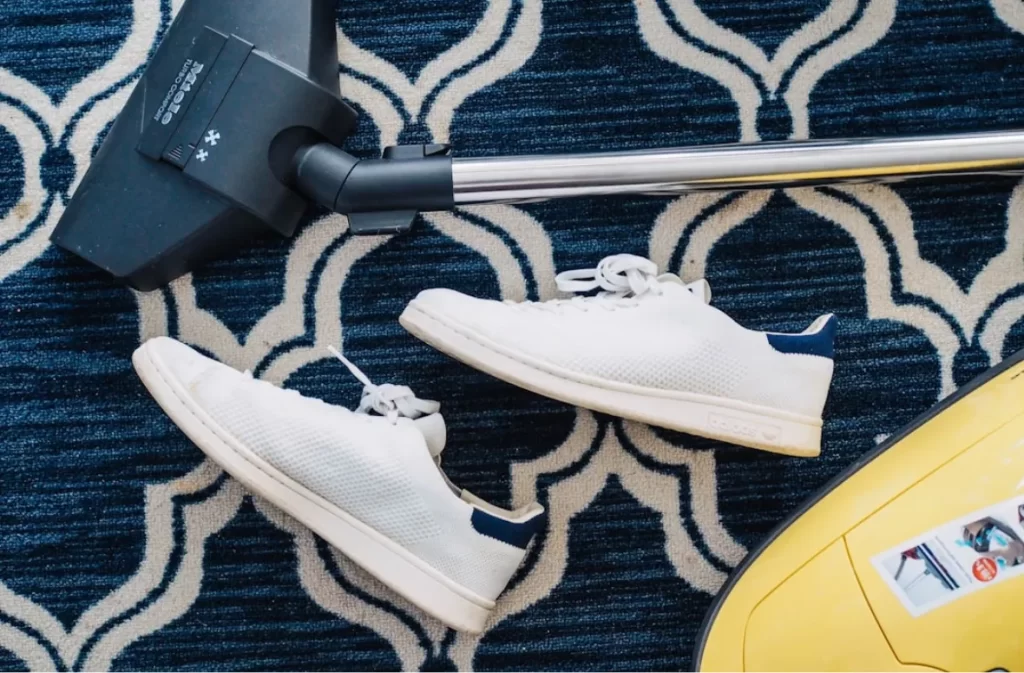 Blue geometric patterned carpet with white sneakers.