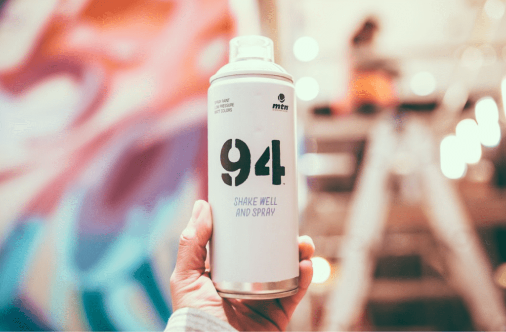 Close-up of spray can labeled "94" in hand.