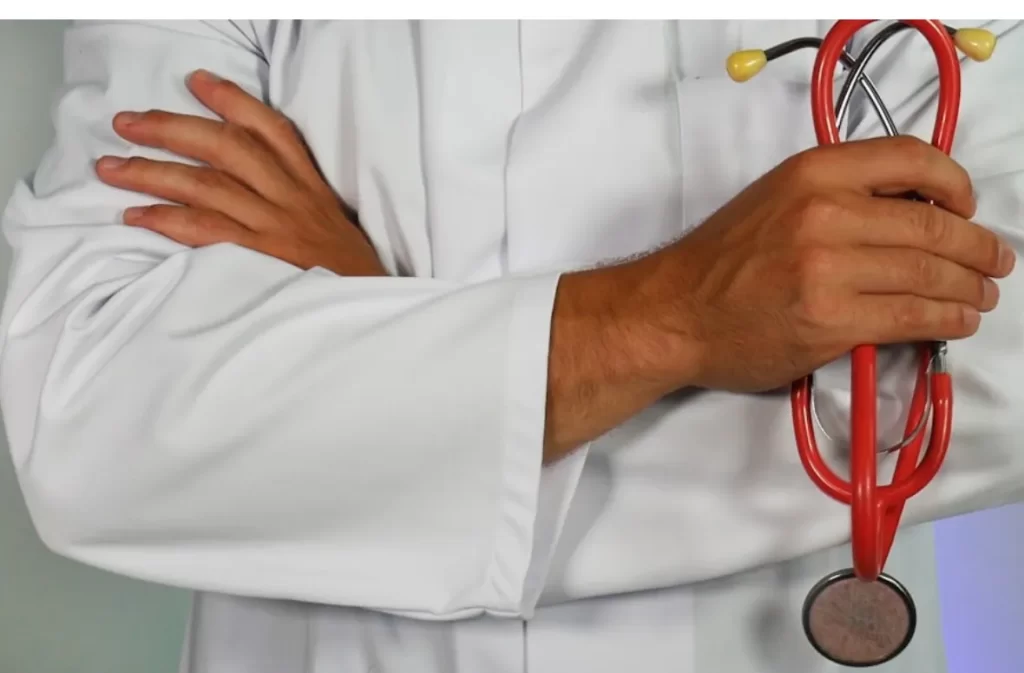 Doctor in scrubs holding a stethoscope.
