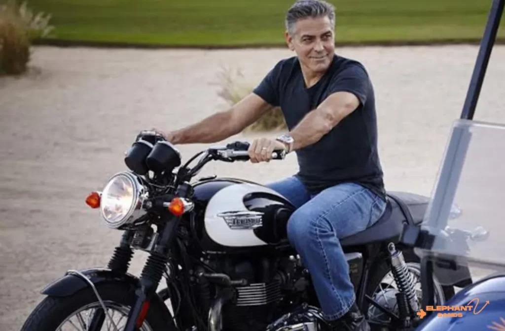 A smiling man on a Harley-Davidson parked on a sandy background.