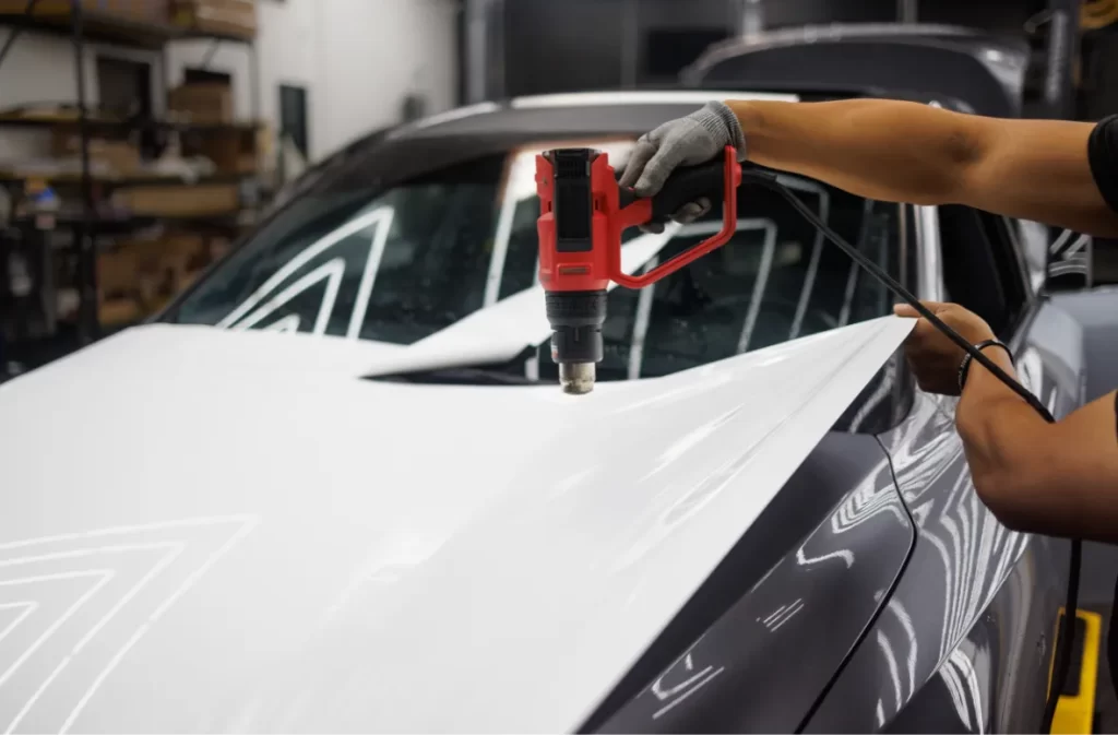 Heat gun being used to apply a white car wrap.