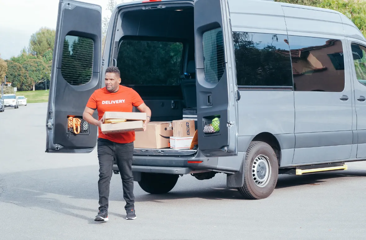 Delivery man in a red shirt carrying boxes from a van.