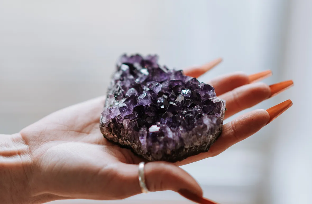 Hand holding a purple geode with sparkling crystals.